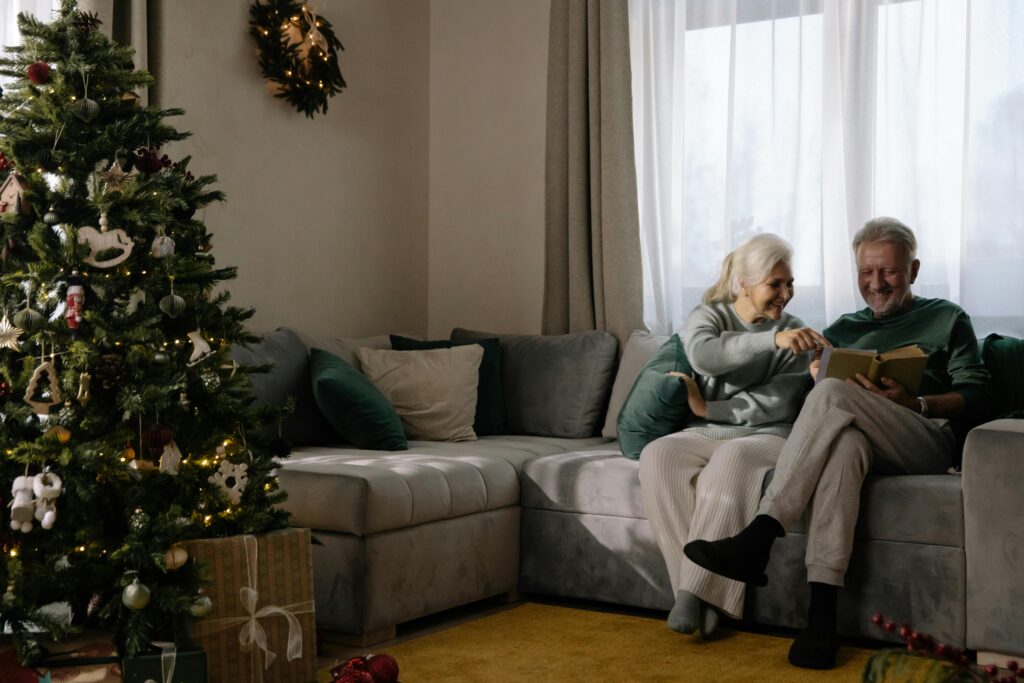 Seniors sitting beside a Christmas tree.